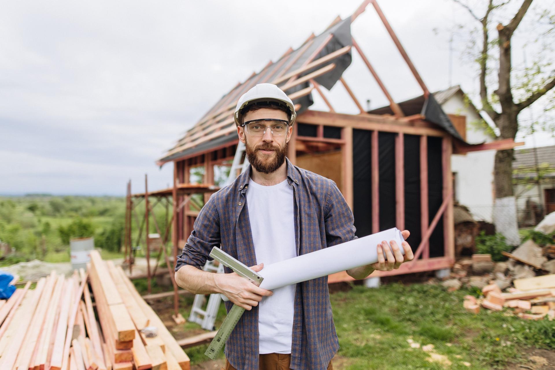 Portrait of Confident Construction Pro with Blueprints at Wood Frame Site