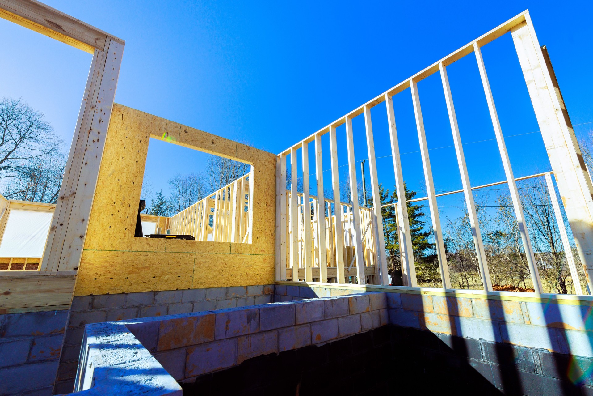 Construction process of a house with wooden framing under a clear blue sky